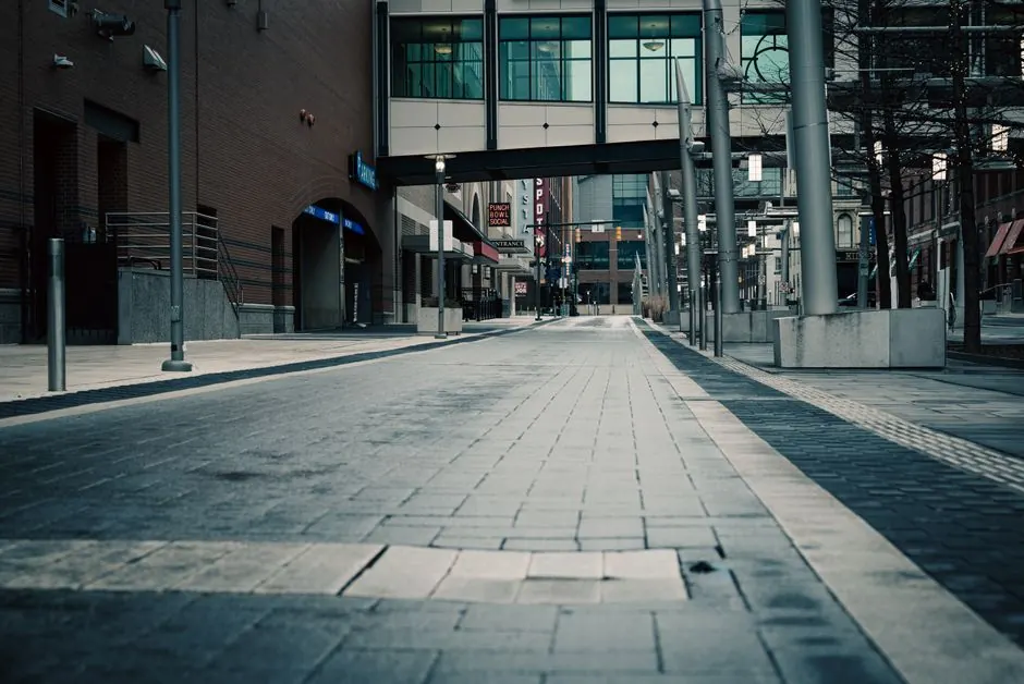 A deserted urban street with modern architecture and glass pedestrian overpass captured in muted tones.
