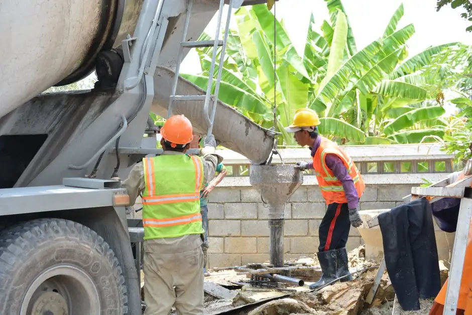 Construction team pouring concrete on site with mixer truck, enhancing a sturdy foundation.