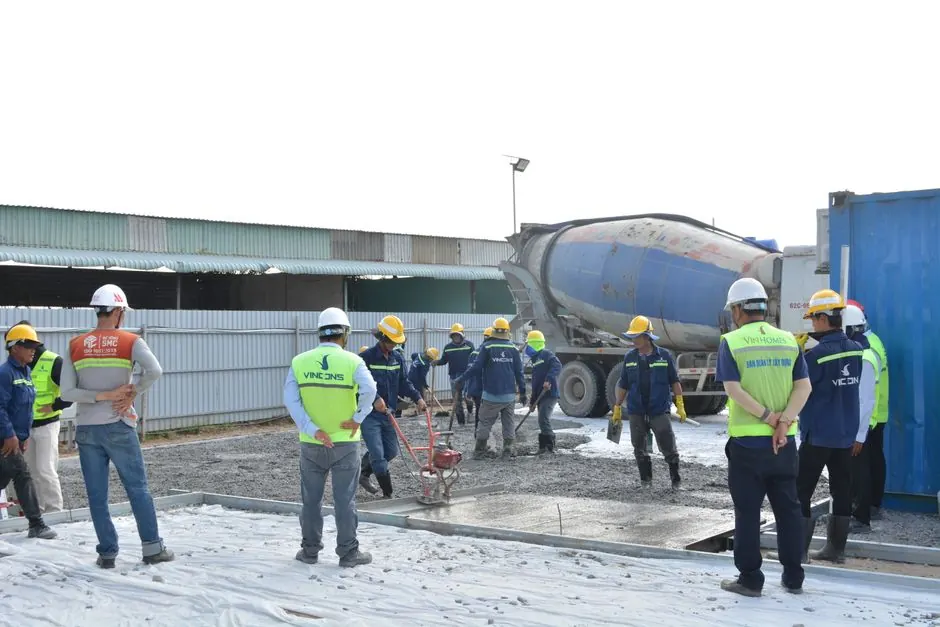 Team of workers in helmets and vests collaborating on a construction site with cement mixer truck.