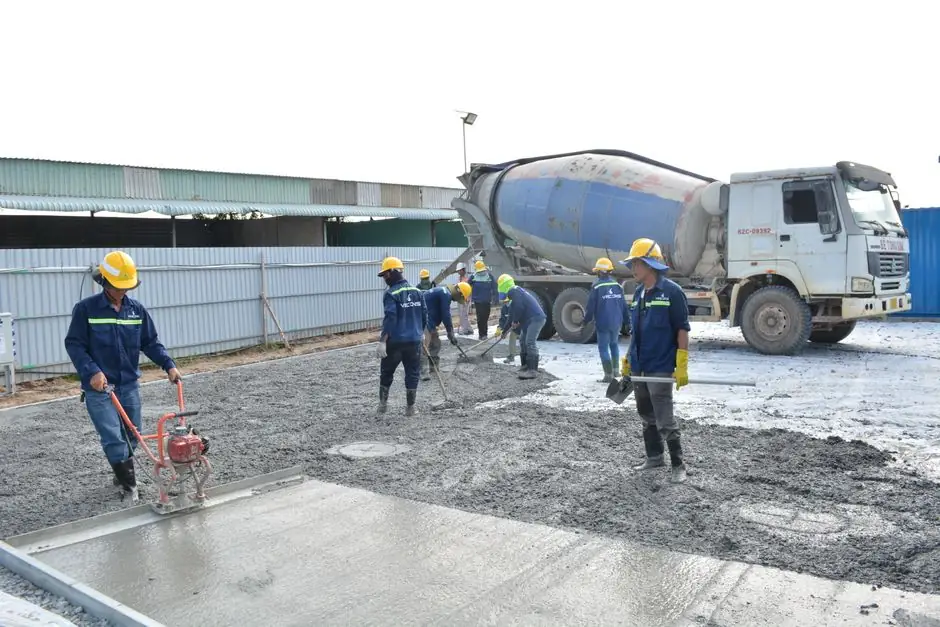 Team of workers pouring cement from a mixer truck on a construction site, ensuring proper leveling.