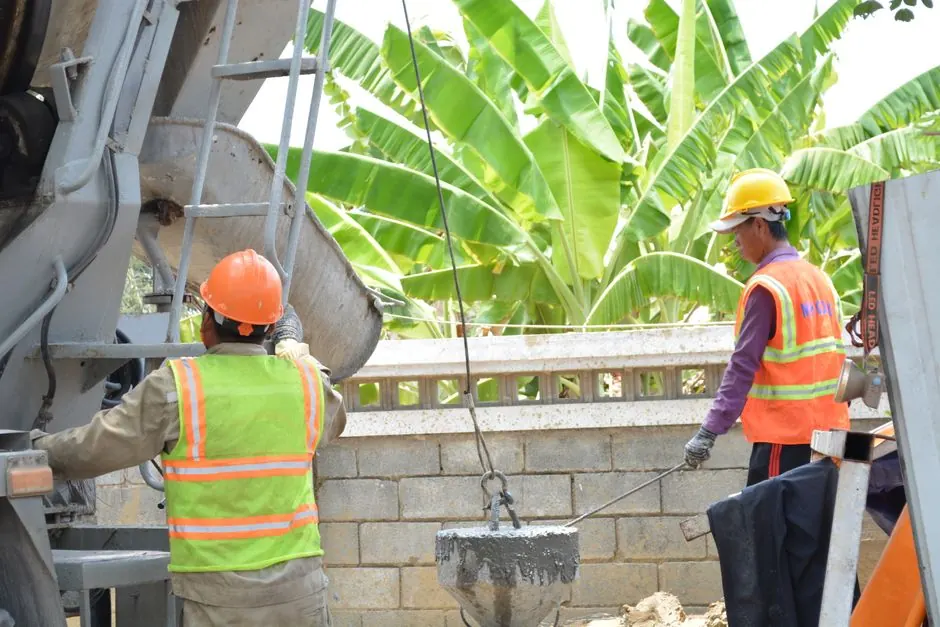 Two construction workers using a concrete mixer for building outdoors, showcasing teamwork and labor.
